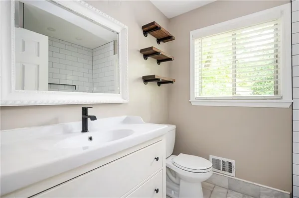 a bathroom with a sink a toilet and a window