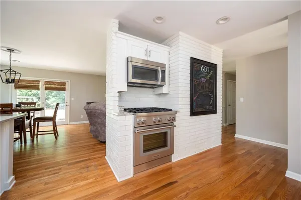 a kitchen with granite countertop a stove top oven a sink dishwasher a dining table and chairs with wooden floor
