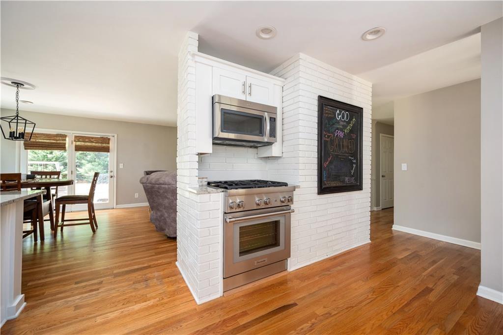 3850 Beya Way Atlanta, GA 30340 - Photo 3 of 18 a kitchen with granite countertop a stove top oven a sink dishwasher a dining table and chairs with wooden floor