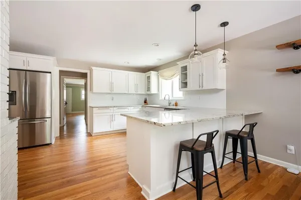 a kitchen with stainless steel appliances granite countertop a refrigerator a sink dishwasher a stove and white cabinets with wooden floor