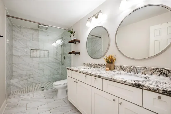 a bathroom with a granite countertop toilet a sink and a mirror