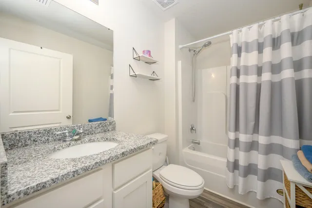 a bathroom with a granite countertop sink toilet and shower