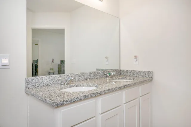 a bathroom with a granite countertop sink and a mirror