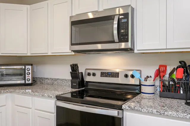 a kitchen with stainless steel appliances granite countertop a stove microwave and cabinets
