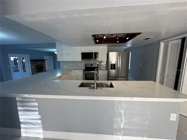 a kitchen with stainless steel appliances a sink a stove top oven a counter space and cabinets