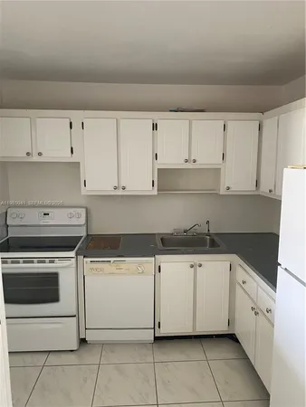 a kitchen with granite countertop white cabinets and white appliances