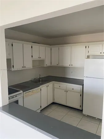 a kitchen with granite countertop white cabinets and white appliances