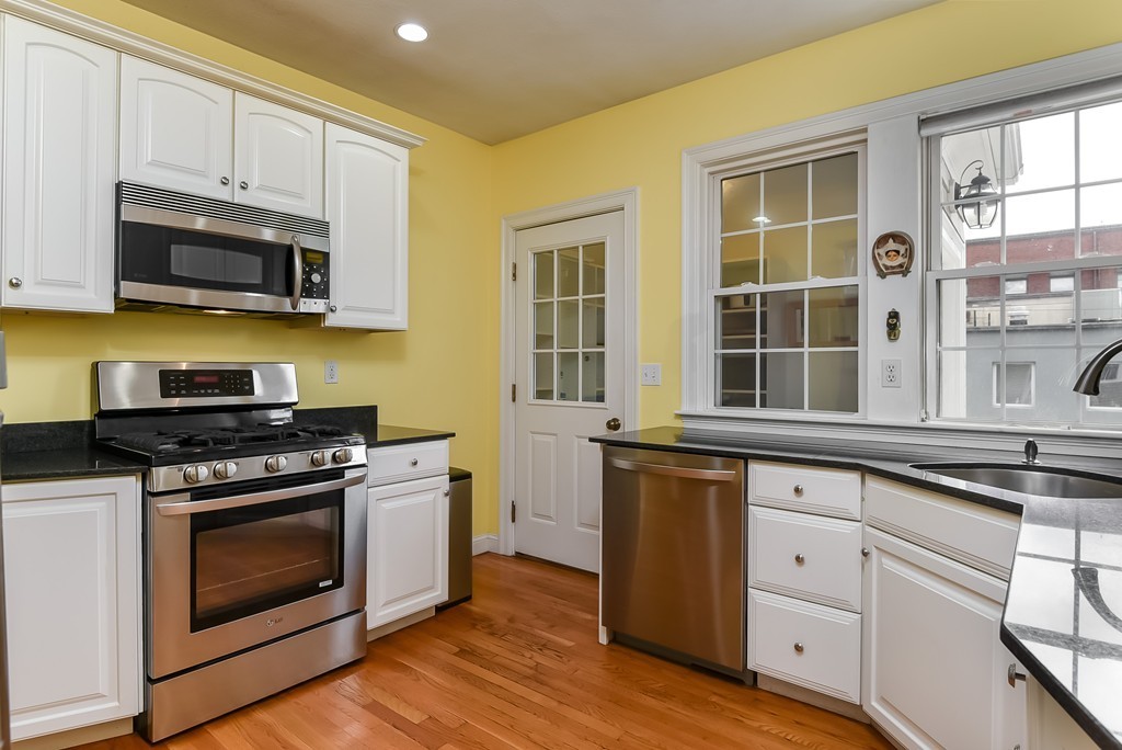 58 Webster Street, Unit 58 Newton, MA 02465 - Photo 5 of 28 a kitchen with stainless steel appliances granite countertop a stove a microwave oven a sink dishwasher and cabinets with wooden floor