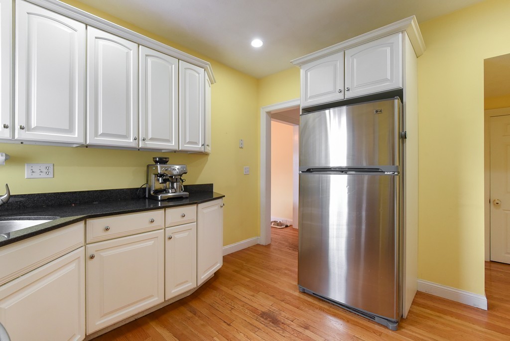 58 Webster Street, Unit 58 Newton, MA 02465 - Photo 6 of 28 a kitchen with granite countertop wooden cabinets and a refrigerator
