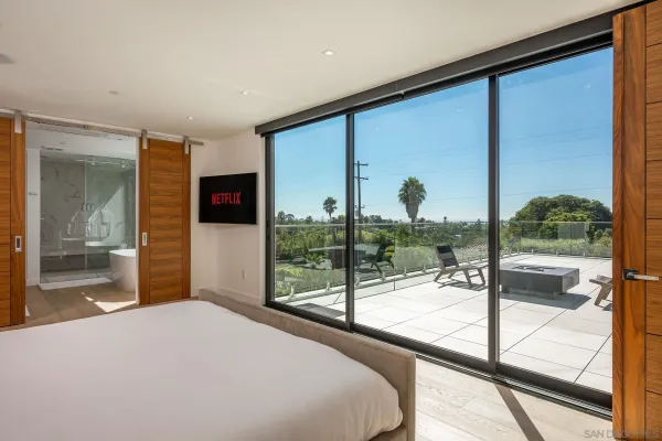 a bedroom with a large window and a balcony