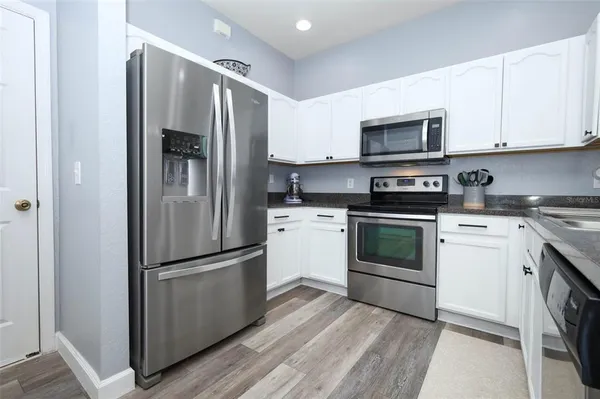 a kitchen with stainless steel appliances a refrigerator sink and white cabinets