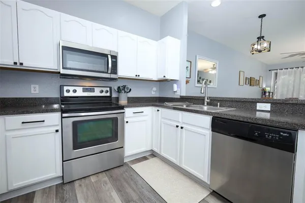 a kitchen with granite countertop white cabinets stainless steel appliances and a sink