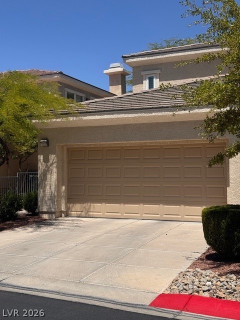 A well-maintained stucco facade with an attached garage and a neatly paved driveway.