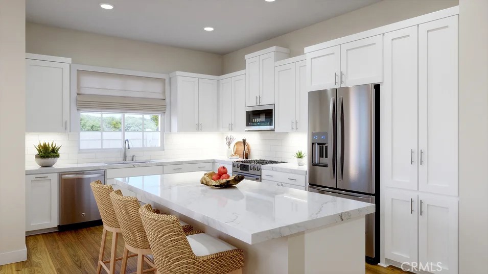a kitchen with stainless steel appliances a sink a microwave a refrigerator and wooden cabinets