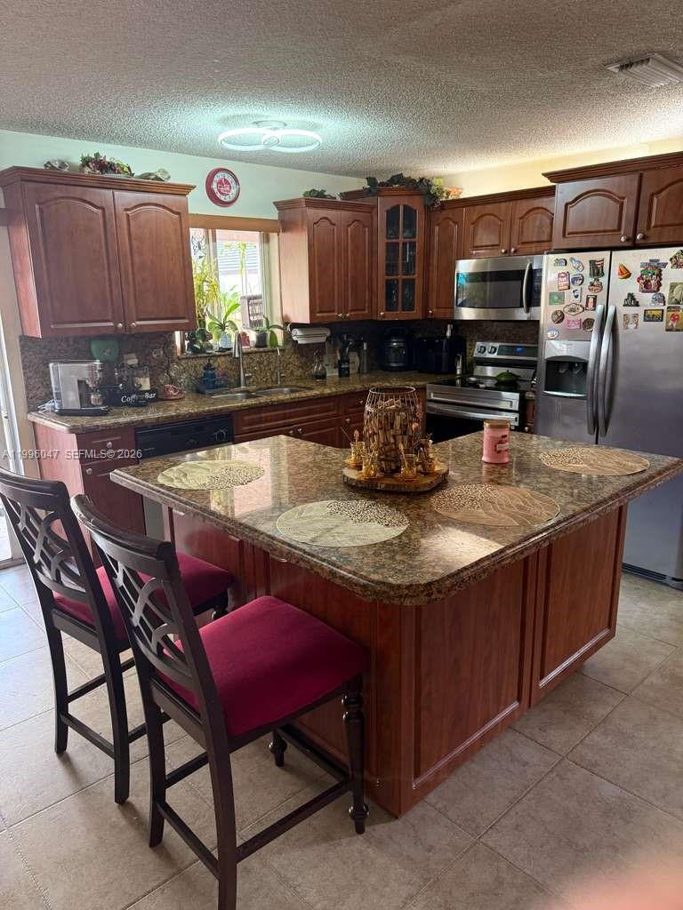 7477 Northwest 167th Street Hialeah, FL 33015 - Photo 8 of 24 a kitchen with a stove a sink and a wooden cabinets