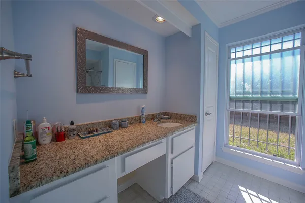 a bathroom with a granite countertop sink and a window