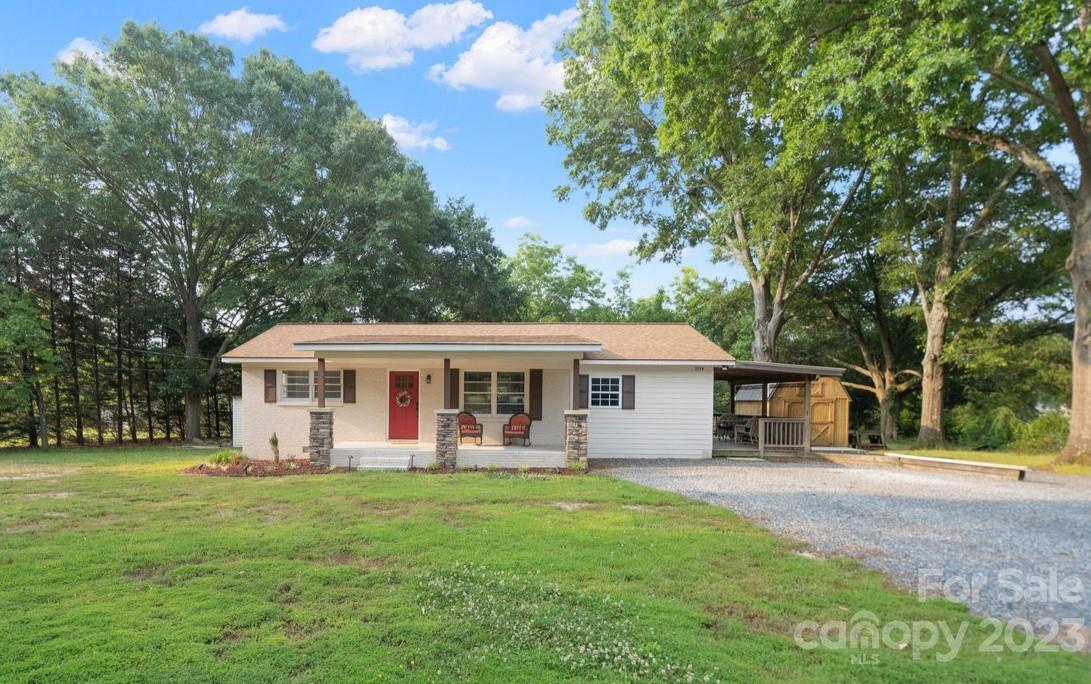 a view of a house with a yard deck and a large tree