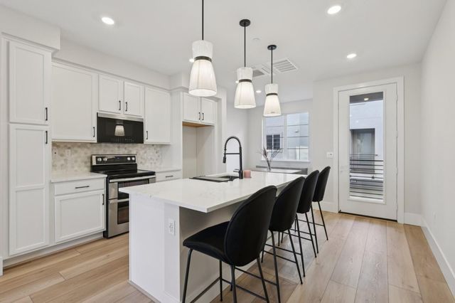 a kitchen with stainless steel appliances a dining table chairs stove and cabinets