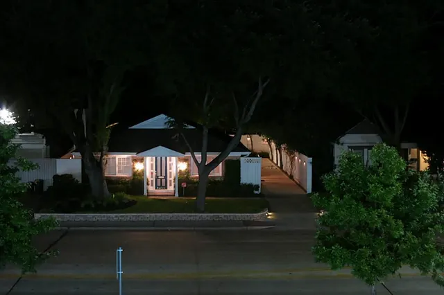 a view of house with outdoor space and trees in the background