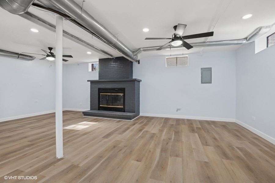 1001 Oakton Street Park Ridge, IL 60068 - Photo 34 of 35 an empty room with wooden floor a ceiling fan a fireplace