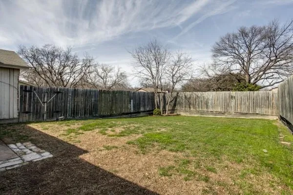 a backyard with wooden fence and a tree