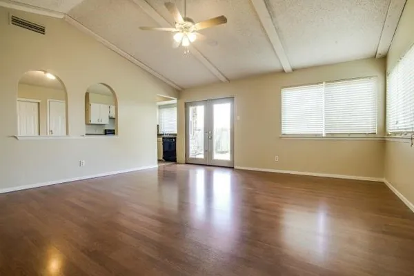 a view of an empty room with wooden floor and a window