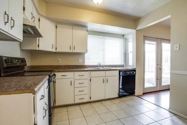 a kitchen with granite countertop a stove sink and cabinets
