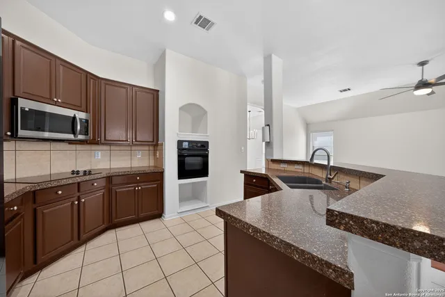 a kitchen with granite countertop a sink a stove top oven and refrigerator