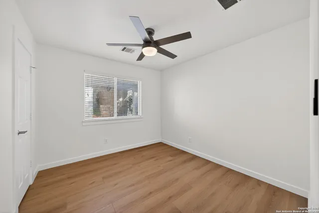 a view of empty room with wooden floor and fan