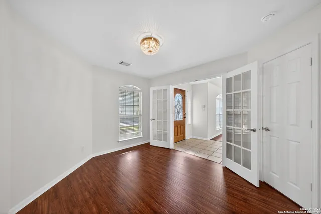 an empty room with wooden floor and windows