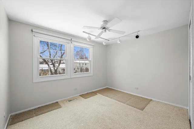 an empty room with windows and fan