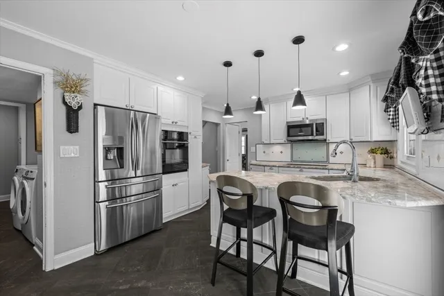 a kitchen with stainless steel appliances kitchen island a table chairs refrigerator and sink