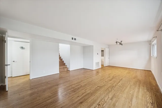 an empty room with wooden floor windows and ceiling fan