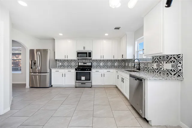 a large kitchen with stainless steel appliances granite countertop a stove a sink and a granite counter tops