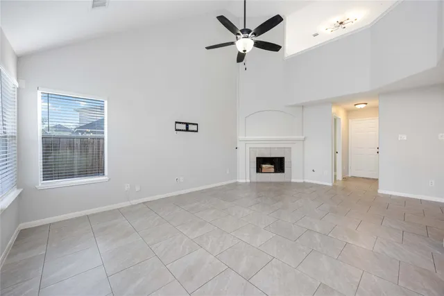 a view of a livingroom with a fireplace a ceiling fan and kitchen view