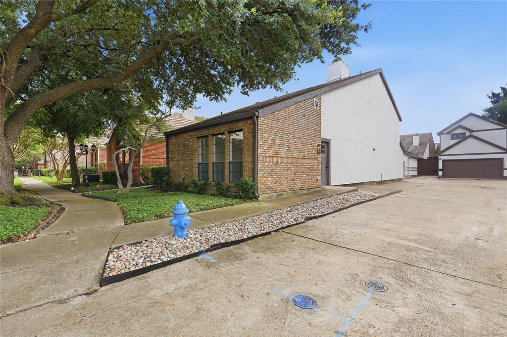 17118 Planters Row Addison, TX 75001 - Photo 3 of 18 Brick and siding exterior featuring large windows, a paved driveway, and established trees
