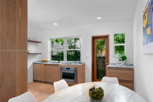 a living room with stainless steel appliances furniture a large window and a fireplace