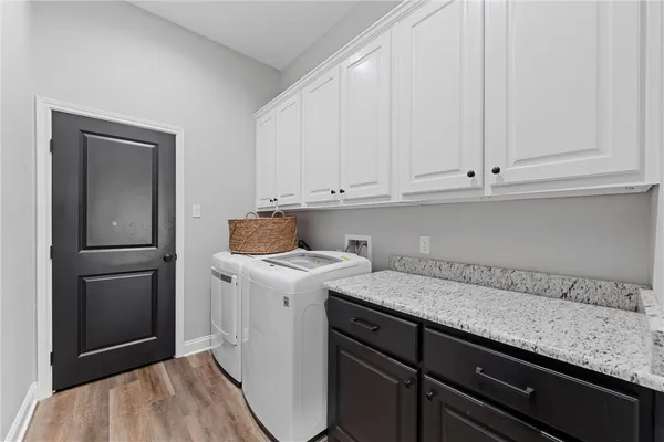 a utility room with granite countertop cabinets washer and dryer