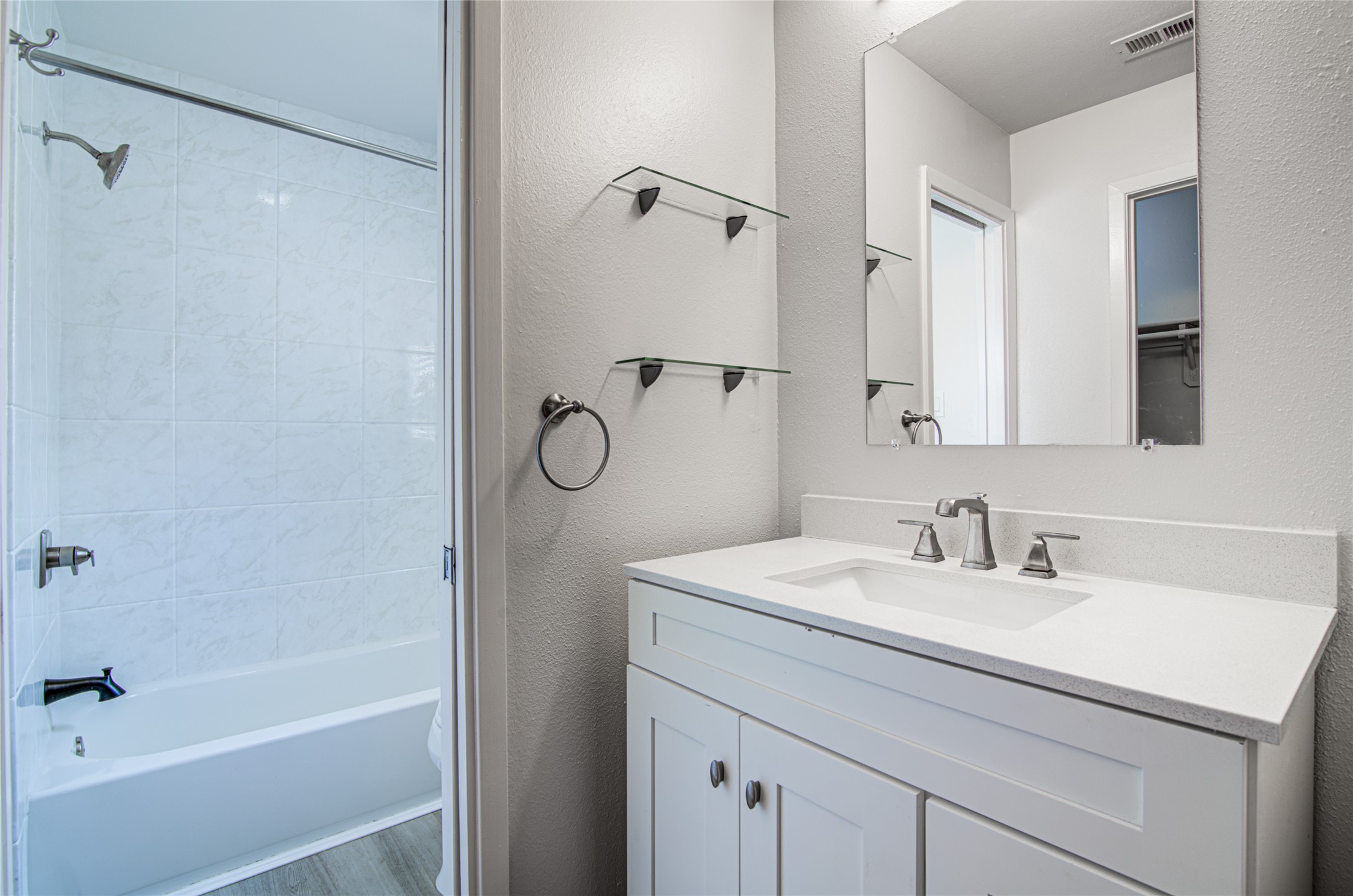 311 West Mary Street Austin, TX 78704 - Photo 12 of 35 Modern bath with a white vanity and gleaming countertop, featuring a sleek mirror and glass shelving.