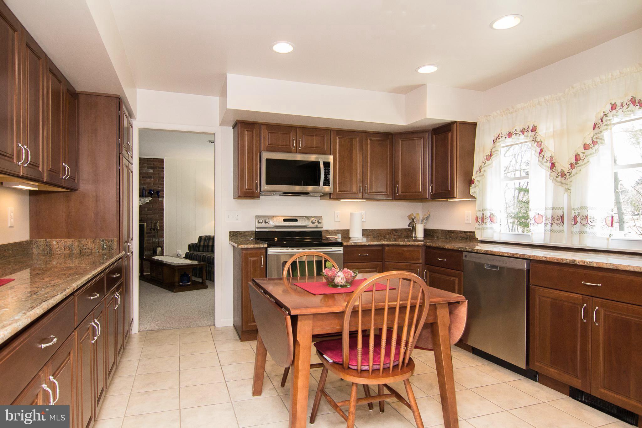 1104 Sturbridge Road Fallston, MD 21047 - Photo 4 of 28 a kitchen with stainless steel appliances granite countertop a stove top oven a sink dishwasher a dining table and chairs with wooden floor
