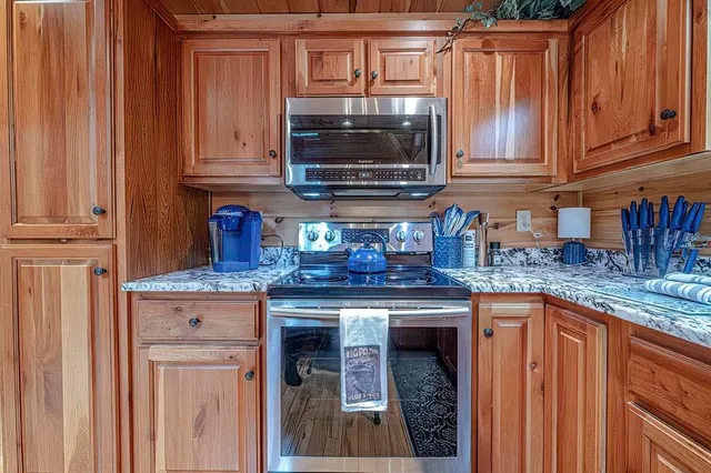 a kitchen with granite countertop a stove top oven microwave and cabinets