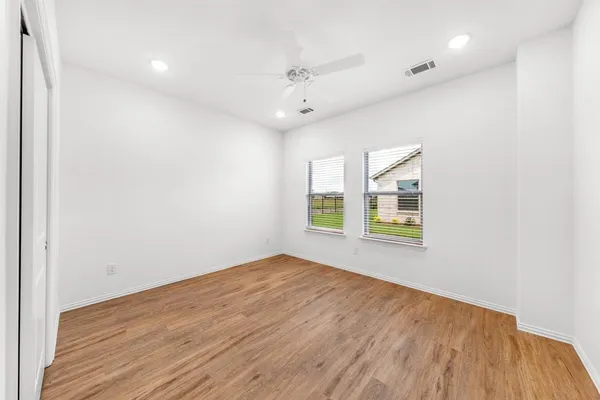 an empty room with wooden floor and fan