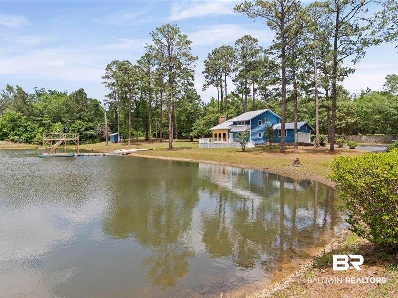 3160 Old Castleberry Road Brewton, AL 36426 - Photo 21 of 36 Waterfront property featuring a blue exterior, a dock with a platform, a boat ramp, and mature trees