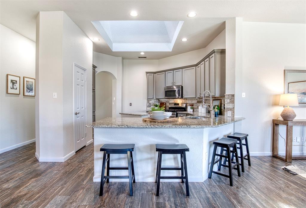 10814 Spring Lake Road Frisco, TX 75035 - Photo 11 of 40 a kitchen with stainless steel appliances a dining table chairs microwave and stove