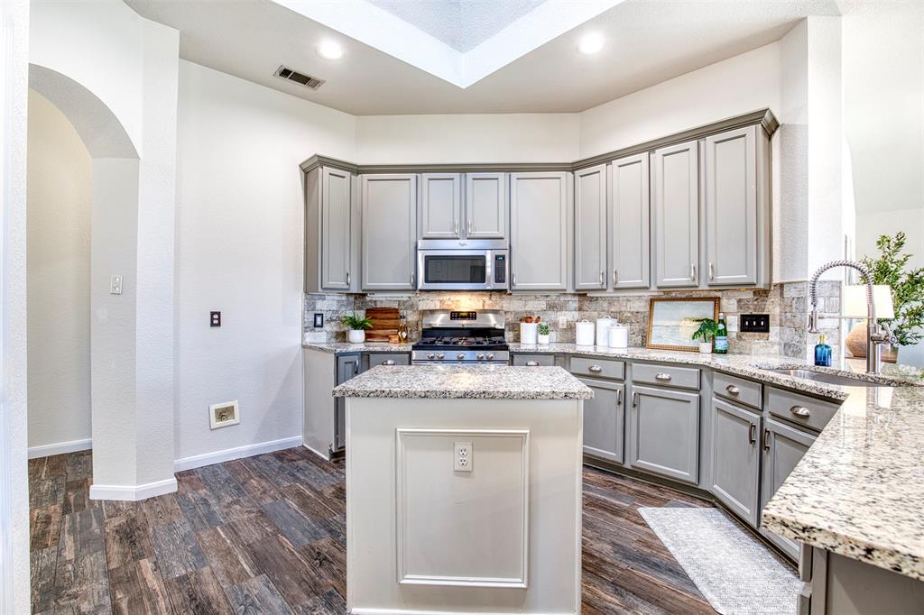 10814 Spring Lake Road Frisco, TX 75035 - Photo 9 of 40 a kitchen with stainless steel appliances granite countertop a stove top oven a sink dishwasher and a refrigerator with wooden floor