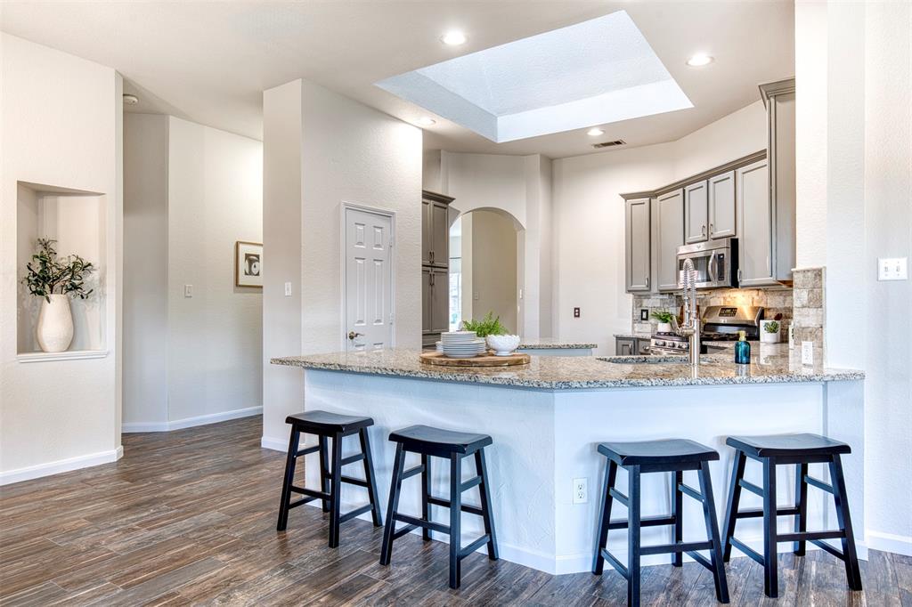10814 Spring Lake Road Frisco, TX 75035 - Photo 10 of 40 a kitchen with granite countertop a table chairs stove microwave and cabinets