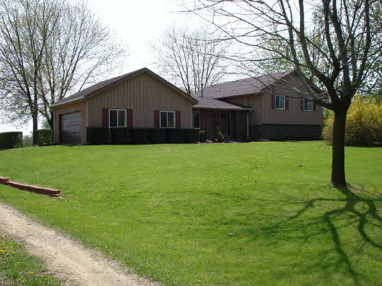7823 East Rockton Road Roscoe, IL 61073 - Photo 1 of 6 a house that is sitting in the grass with tress in the background