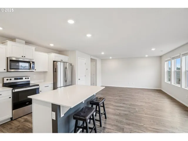 a kitchen with stainless steel appliances a kitchen island hardwood floor sink stove dining table and chairs