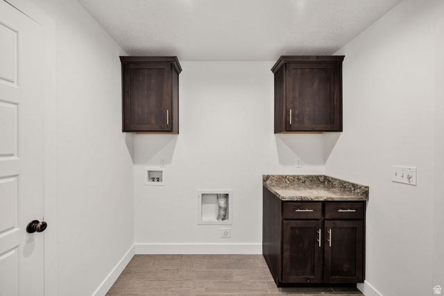 1552 Sumac Drive Logan, UT 84321 - Photo 49 of 72 Laundry area featuring white walls, wood-finish tile flooring, a dark wood-finish base cabinet with a stone-finish countertop, and matching dark wood-finish upper cabinetry