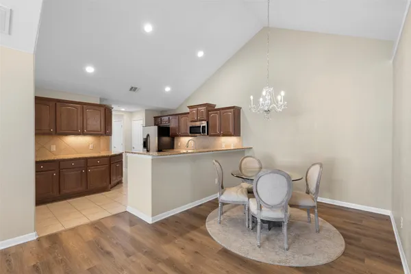 a kitchen with granite countertop a dining table chairs stainless steel appliances and cabinets
